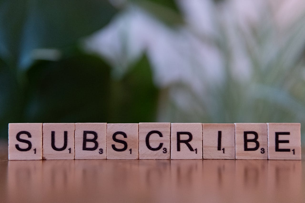 why-choose-us Close-up of the word SUBSCRIBE spelled with wooden letter tiles on a table.