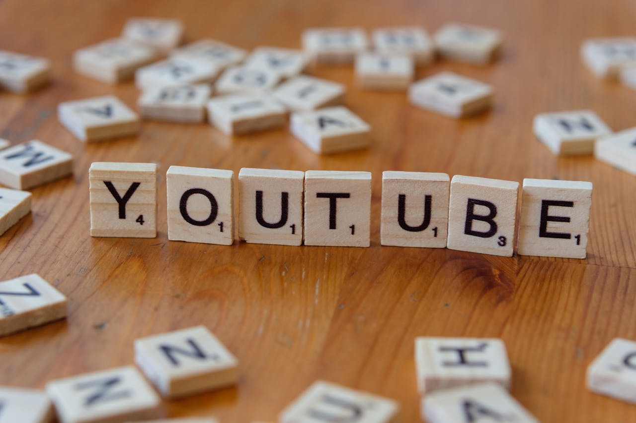 hero-img-01 Wooden letter tiles spelling YOUTUBE on a wooden surface, symbolizing video sharing and streaming.